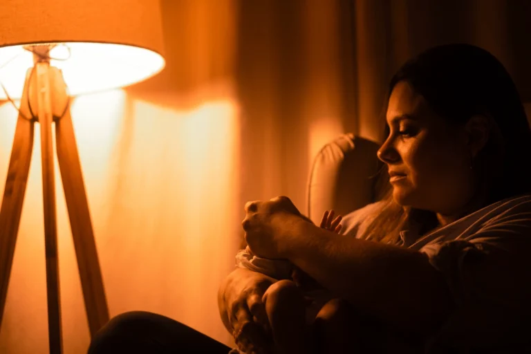 Parent rassurant son bébé la nuit sous une lumière douce